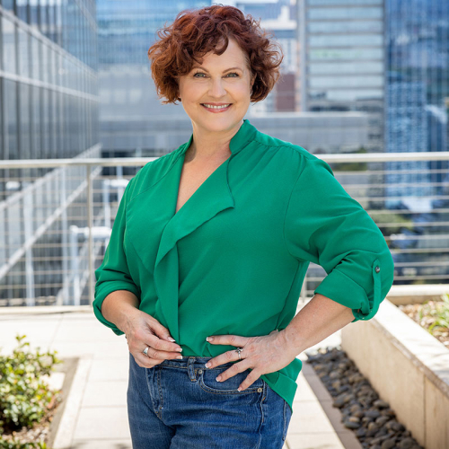 Headshot of Jean Lucy, wearing a green blouse, with a city skyline in the background