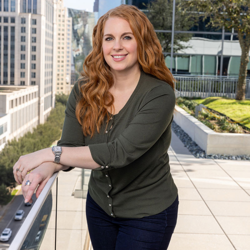 Headshot of Shannon Sodaro, wearing a long-sleeved green blouse, with a city skyline in the background