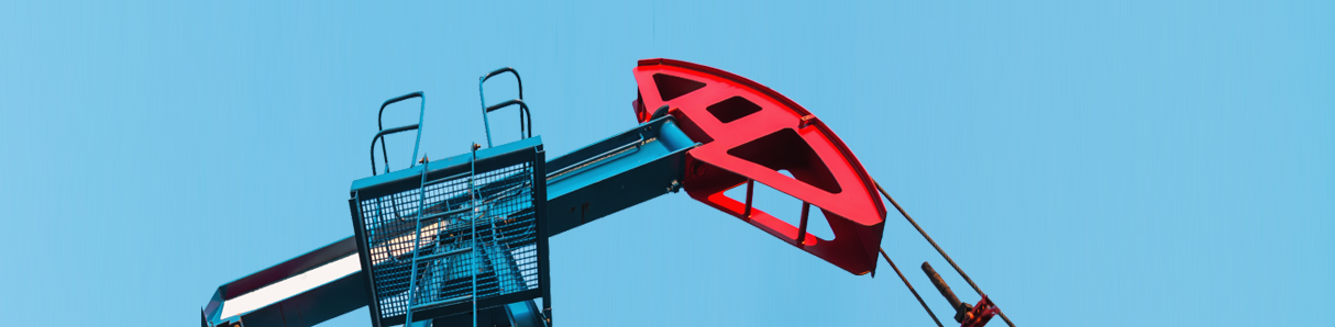 Close-up shot of a red-and-blue, on-land oil rig in action, viewed from beneath with the maintenance platform visible