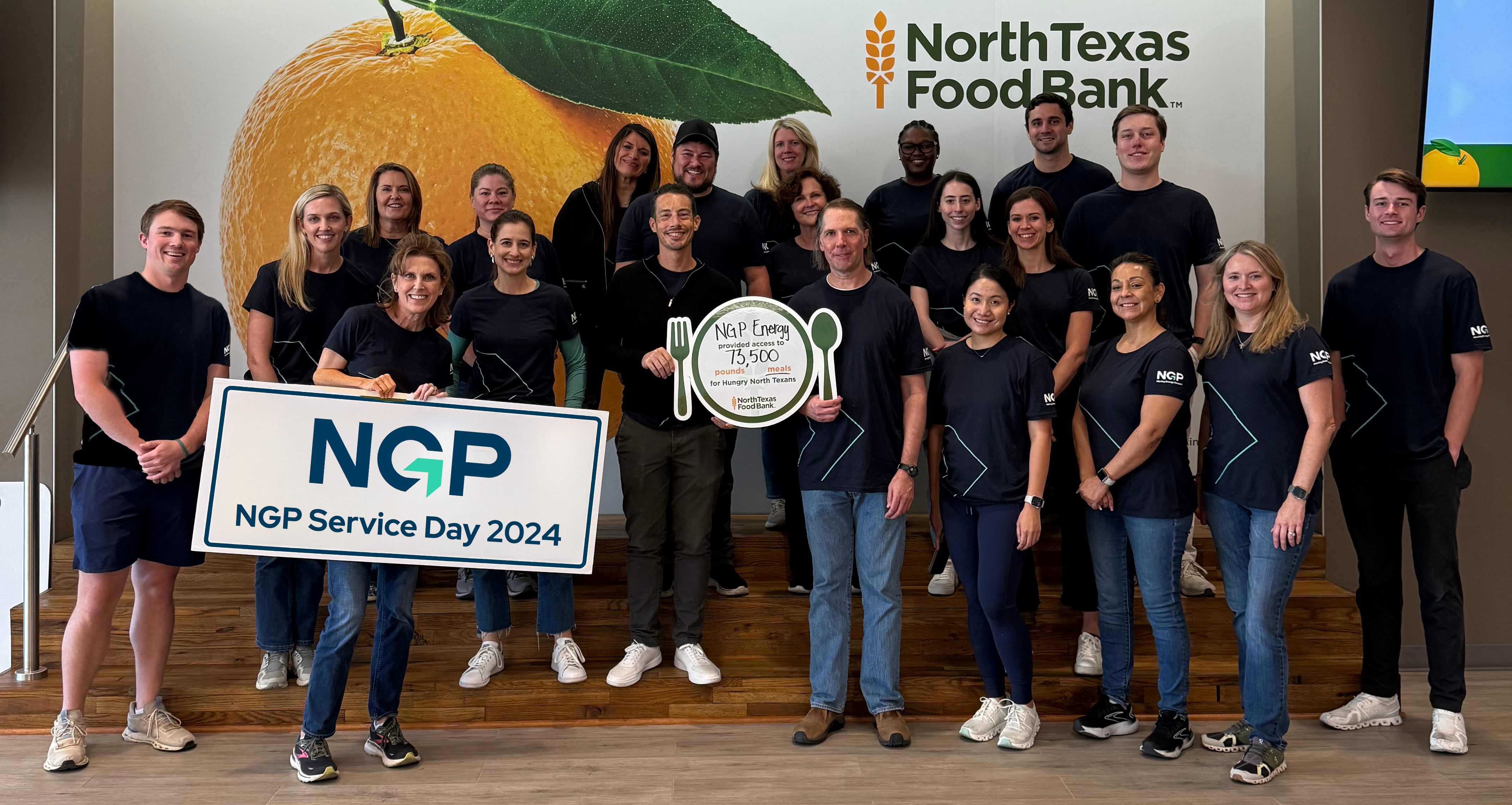 Large croup of NGP employees that participated on Service Day at North Texas Foodbank. Holding Service Day Sign and NTFB plackard with meals provided.